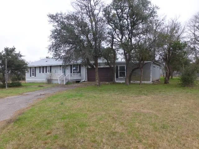 a view of a house with a yard and a large tree