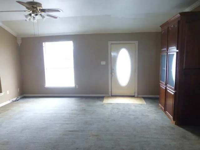 an empty room with chandelier fan and windows