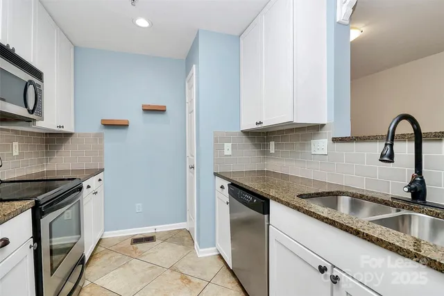 a kitchen with granite countertop a sink stainless steel appliances and cabinets