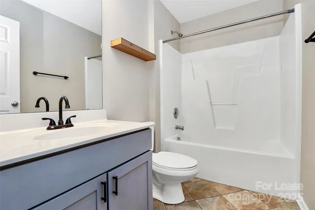 a bathroom with a granite countertop sink a toilet and shower