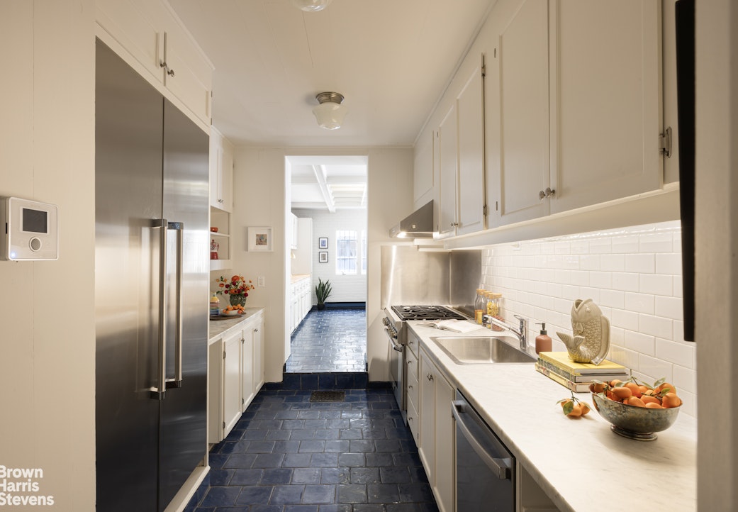 57 East 74th Street Manhattan, NY 10021 - Photo 15 of 60 a kitchen with stainless steel appliances a sink a stove a refrigerator and cabinets