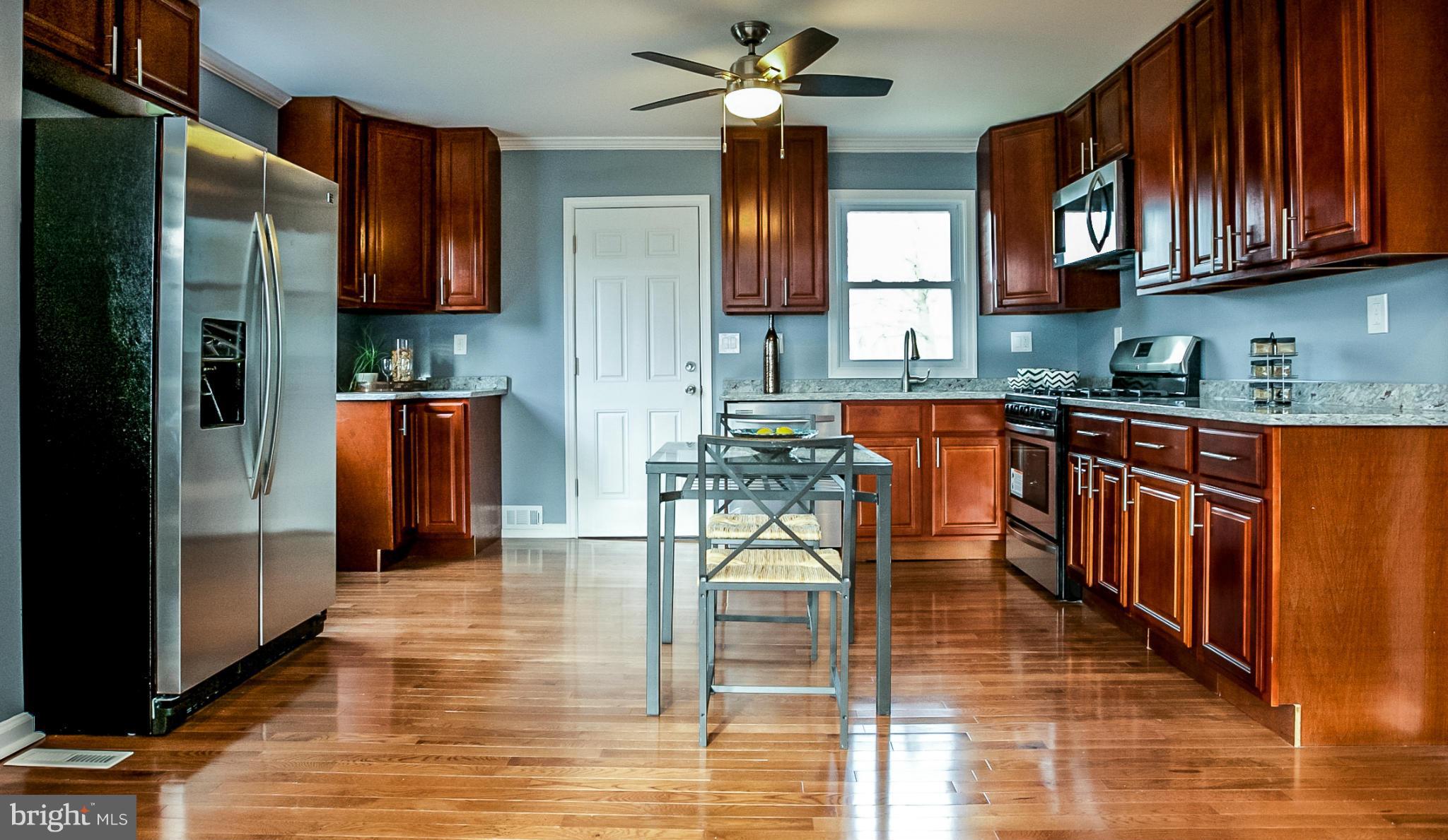 3534 Milford Mill Road Baltimore, MD 21244 - Photo 2 of 30 a kitchen with stainless steel appliances granite countertop wooden cabinets a refrigerator a stove top oven and a dishwasher