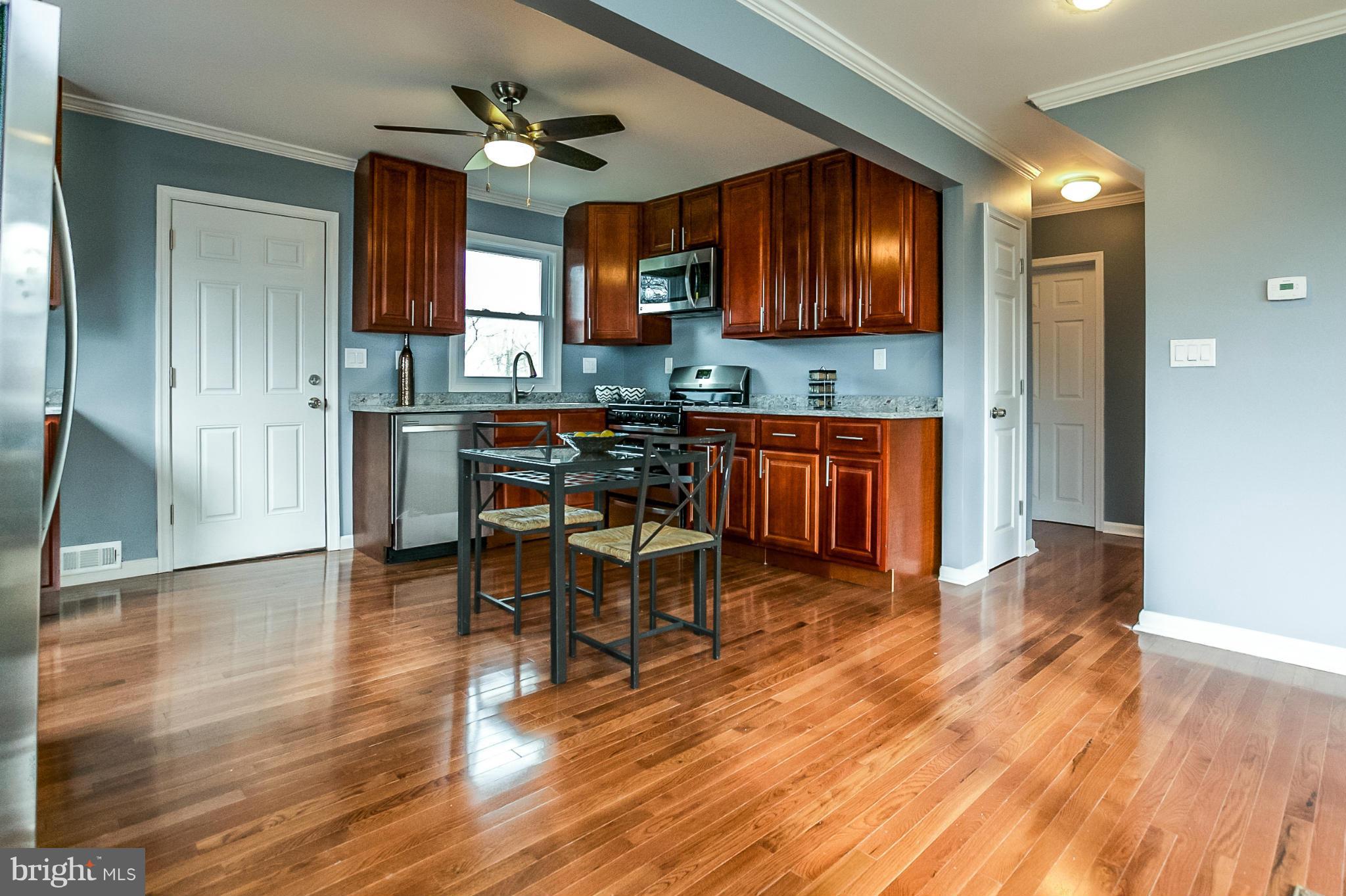 3534 Milford Mill Road Baltimore, MD 21244 - Photo 29 of 30 a kitchen with stainless steel appliances granite countertop wooden cabinets a dining table and chairs