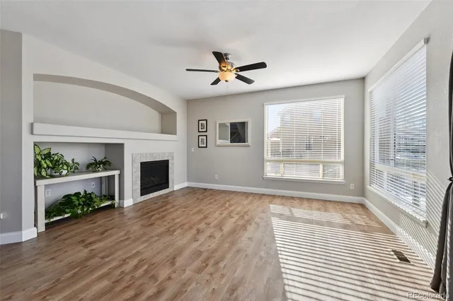 a view of a livingroom with a fireplace a ceiling fan and a kitchen view