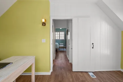 a view of a hallway with wooden floor windows and a bathroom
