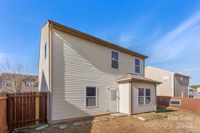 a view of a house with backyard and wooden fence