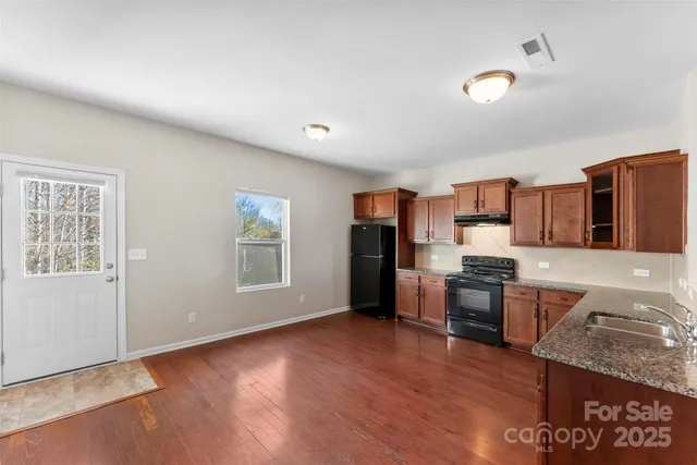 a view of kitchen with stainless steel appliances granite countertop a stove top oven a sink dishwasher and wooden floor