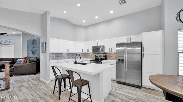 a kitchen with stainless steel appliances granite countertop a refrigerator a sink a stove a dining table and chairs