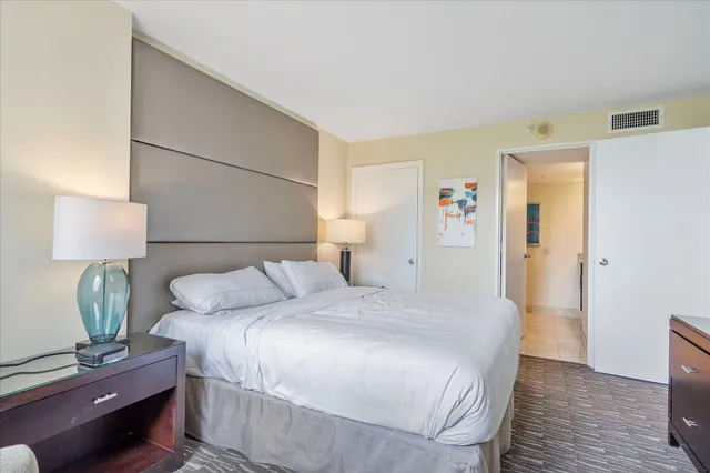 a bedroom with a bed and a lamp on the dresser