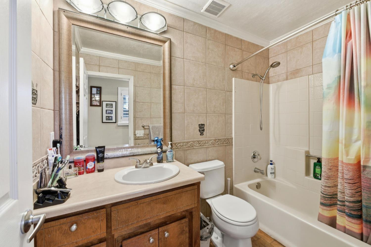 2440 Pleasant Valley Road Placerville, CA 95667 - Photo 14 of 40 full bathroom featuring vanity, crown molding, shower / bath combination with curtain, and tile walls