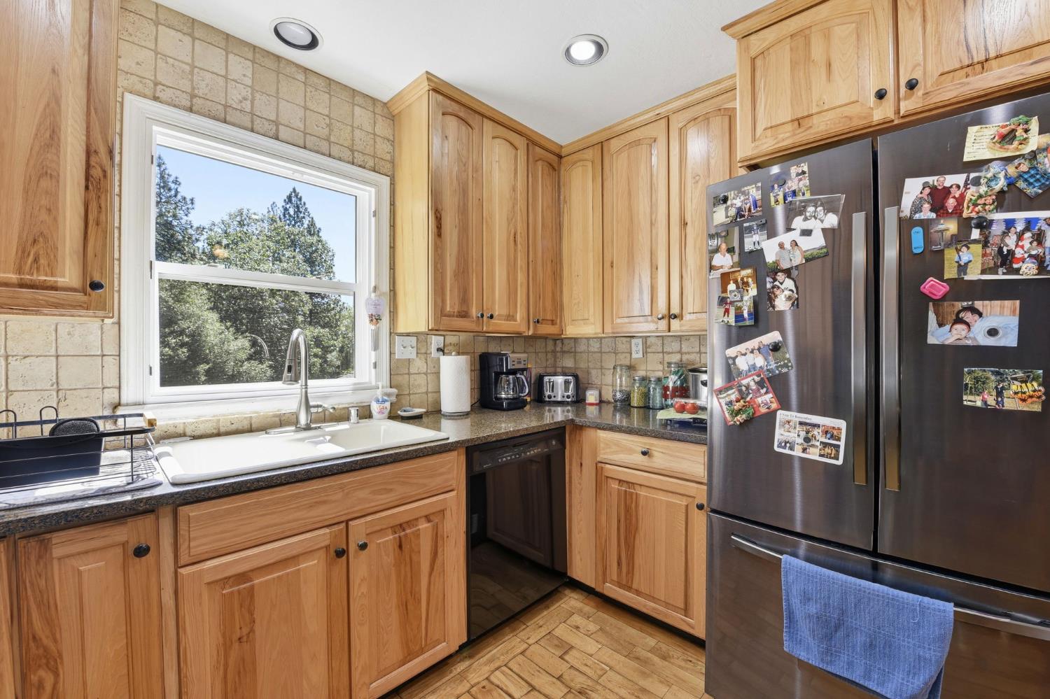 2440 Pleasant Valley Road Placerville, CA 95667 - Photo 19 of 40 kitchen featuring freestanding refrigerator, dark stone counters, dishwasher, light wood-style flooring, and decorative backsplash