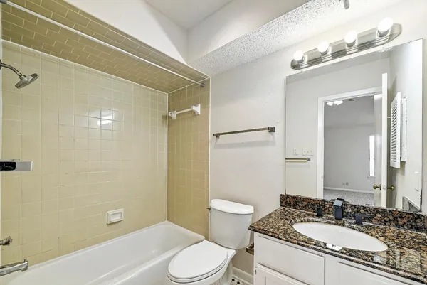 a bathroom with a granite countertop sink toilet a mirror and shower
