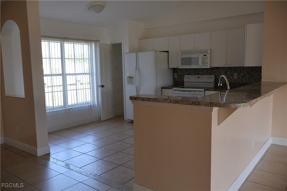 3805 22nd Street Southwest Lehigh Acres, FL 33976 - Photo 9 of 26 a kitchen with stainless steel appliances granite countertop a sink a stove a refrigerator a microwave and cabinets