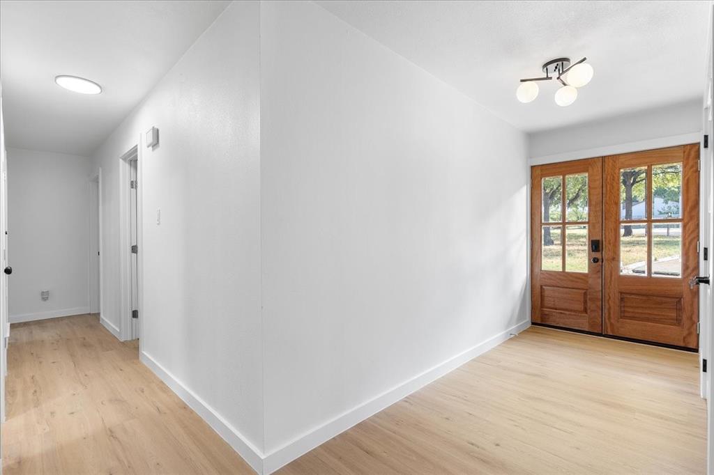 3509 West Sublett Road Arlington, TX 76017 - Photo 19 of 39 Wood-finish flooring throughout, bright white walls, modern ceiling light fixture, and wood-paneled double entry doors with glass lites