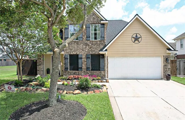 a view of a house with brick walls and a yard with plants