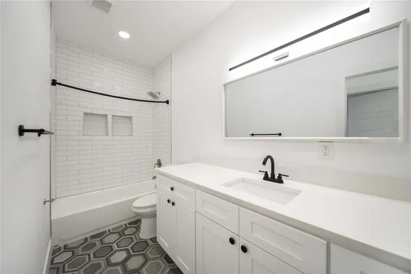 a bathroom with a sink a toilet a mirror and shower