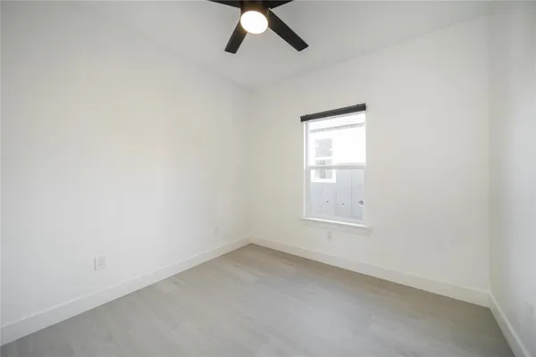 an empty room with a window and a fan