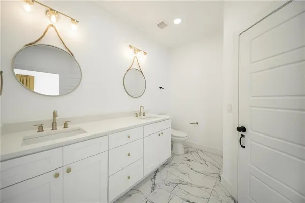a bathroom with a double vanity sink mirror and toilet