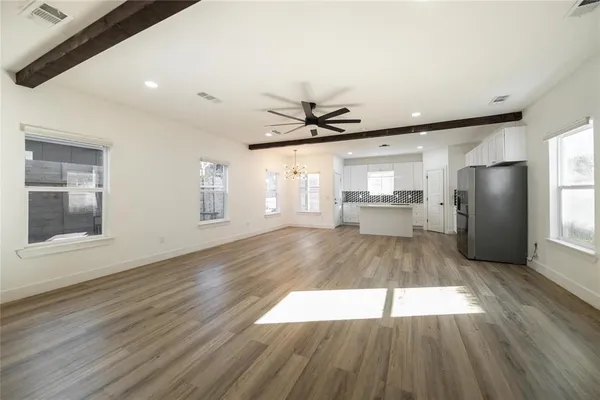 a view of a kitchen with wooden floor a ceiling fan and windows