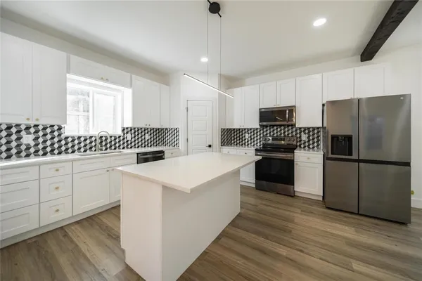 a kitchen with a refrigerator a sink and dishwasher with wooden floor