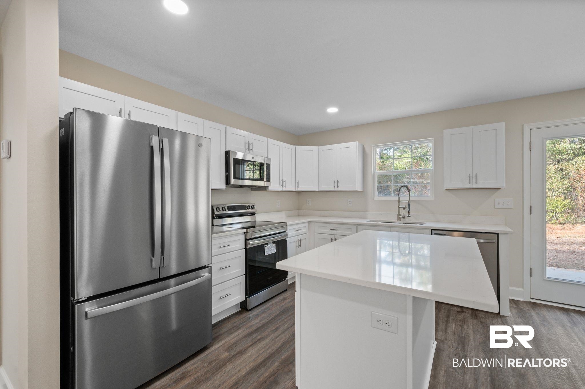 1473 Pollard Road Daphne, AL 36526 - Photo 14 of 32 Kitchen featuring appliances with stainless steel finishes, sink, white cabinets, dark hardwood / wood-style flooring, and a center island
