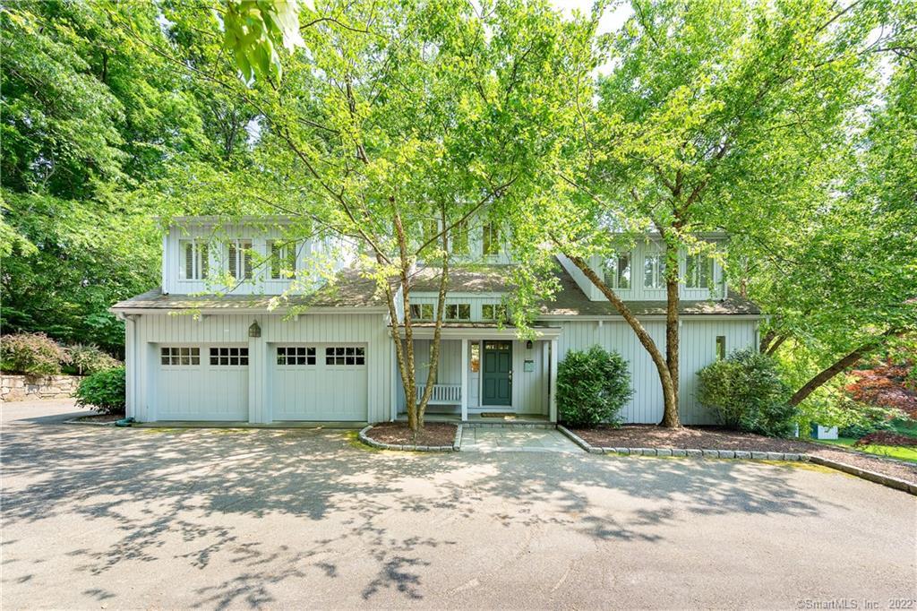 a view of a white house next to a yard with large trees