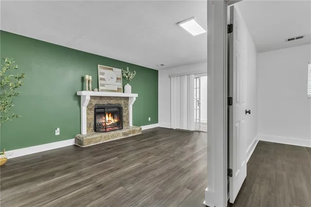 a view of an empty room with wooden floor and a fireplace