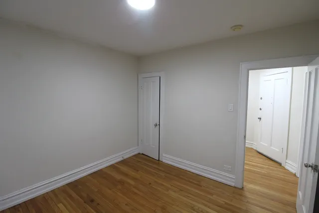 a view of an empty room with wooden floor and closet