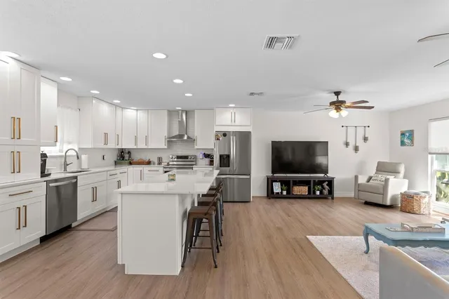 a living room with furniture kitchen view and a wooden floor