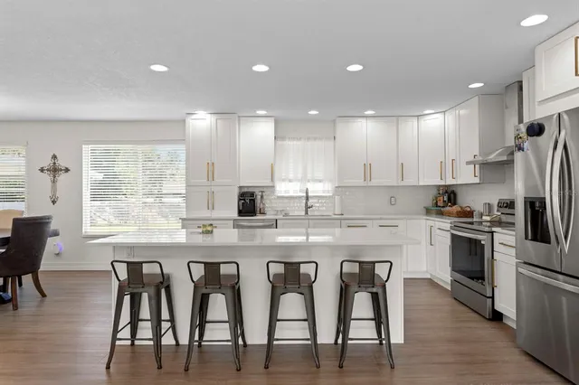 a kitchen with stainless steel appliances granite countertop a table chairs sink refrigerator and microwave