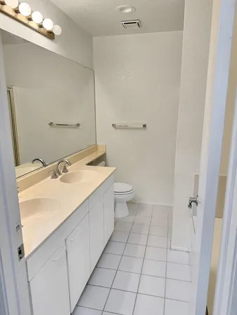 a spacious bathroom with a sink a toilet and a mirror