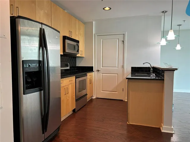 a kitchen with stainless steel appliances granite countertop a refrigerator a stove a microwave and a sink