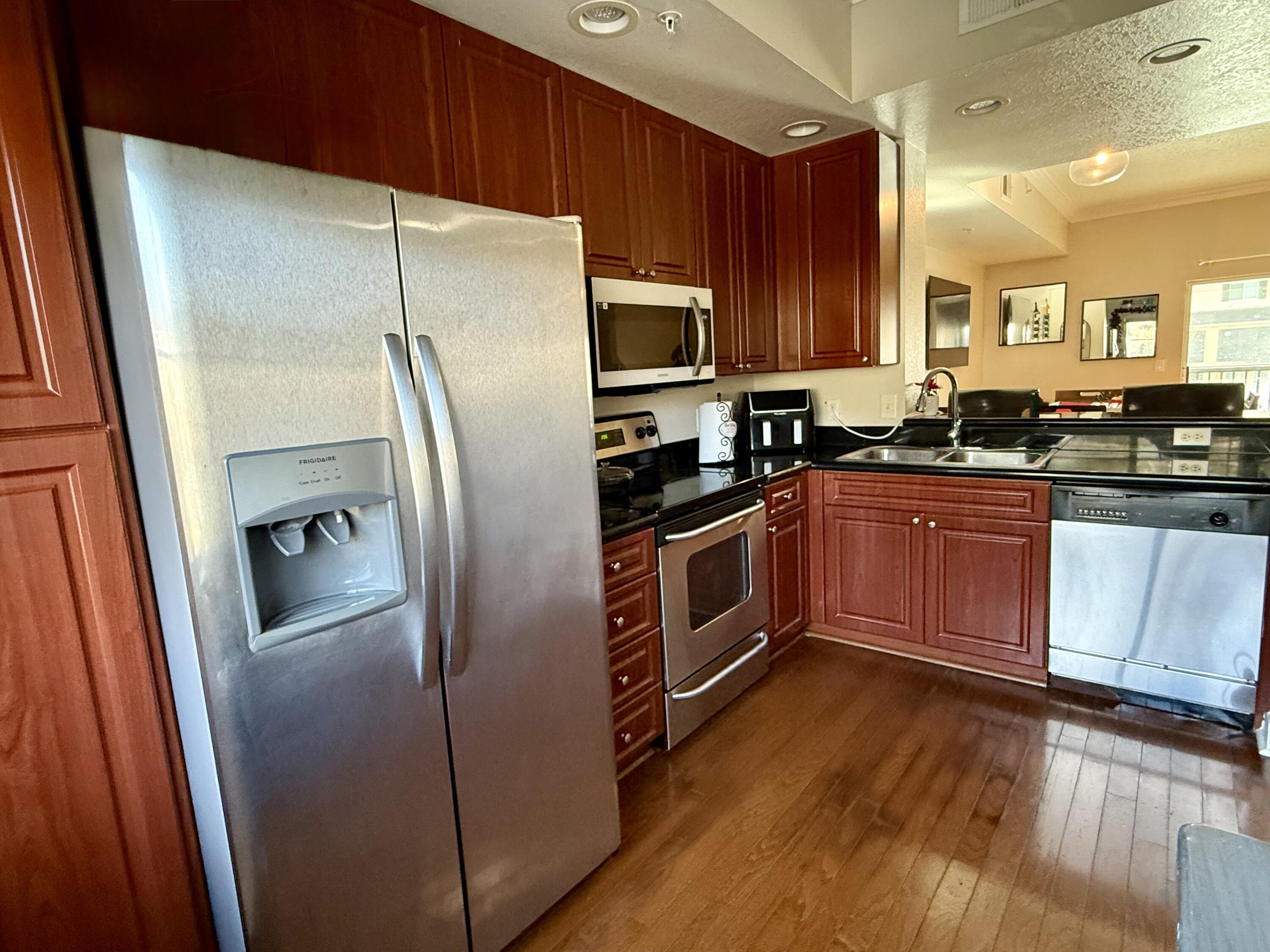 9745 Touchton Road, Unit 1726 Jacksonville, FL 32246 - Photo 5 of 40 a kitchen with stainless steel appliances granite countertop a refrigerator a sink a stove a microwave and wooden floors