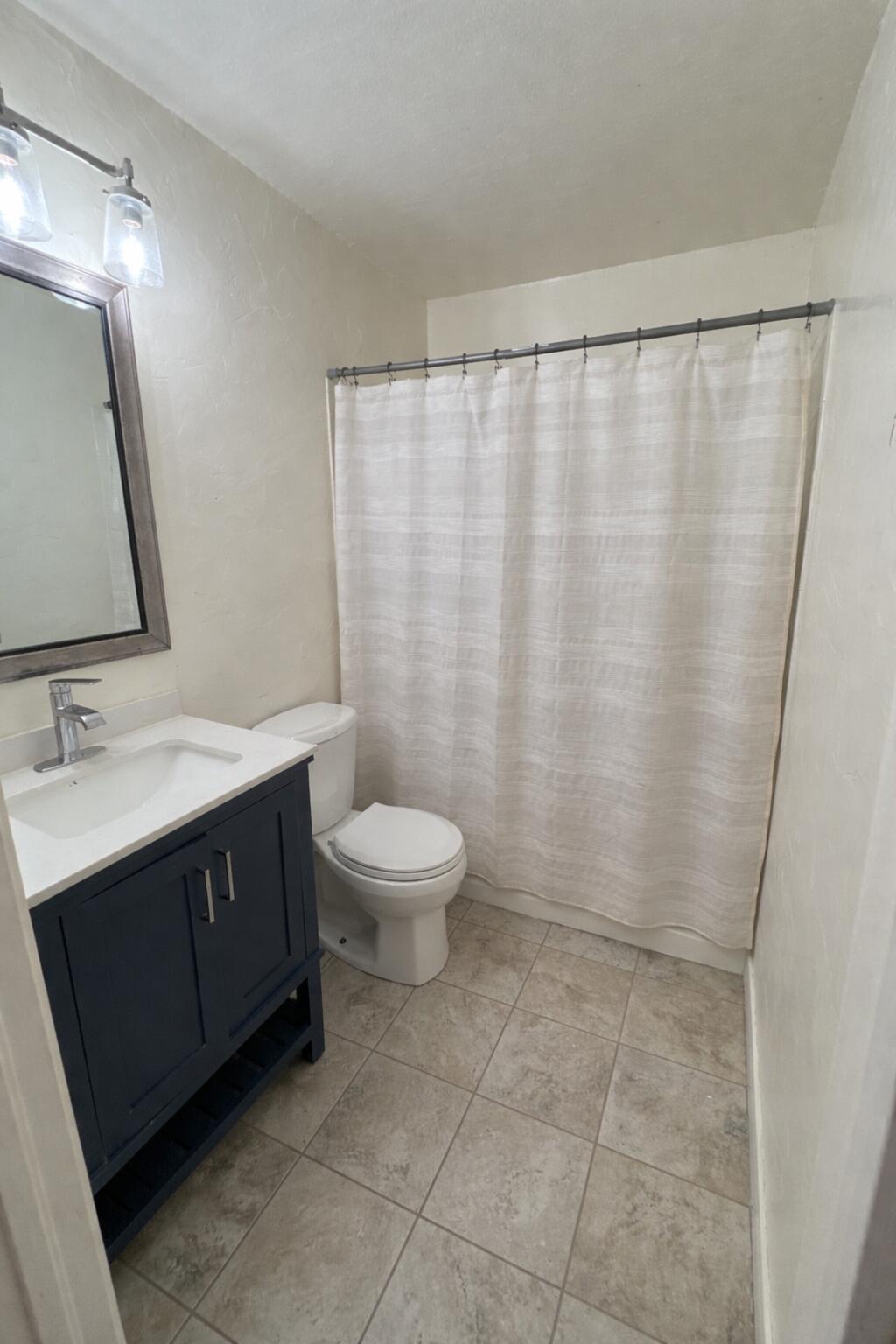 3116 33rd Street Lubbock, TX 79410 - Photo 4 of 7 a bathroom with a sink a toilet a mirror and shower curtain