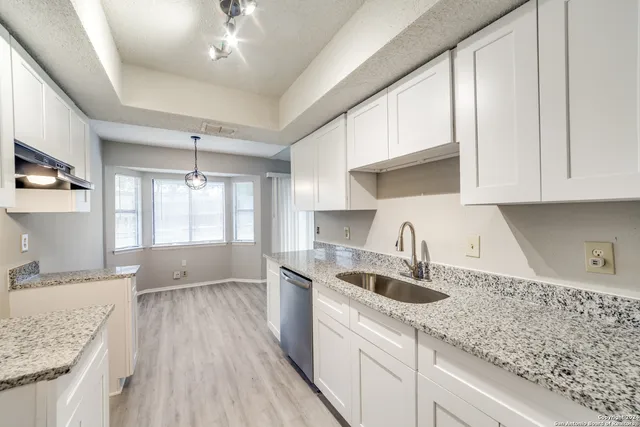 a kitchen with granite countertop a sink a counter space appliances and cabinets