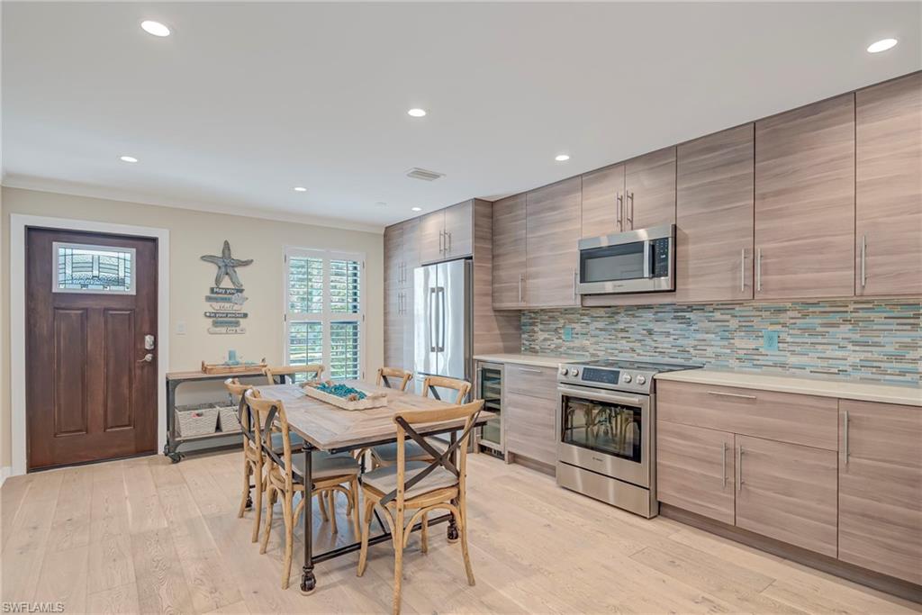 1070 6th Street South, Unit 1070 Naples, FL 34102 - Photo 12 of 41 Gorgeous front door entry with stained glass panel, kitchen impact window with plantation shutters, dining space featuring recessed lighting, wine cooler, updated cabinets and counter, and light wood-style flooring