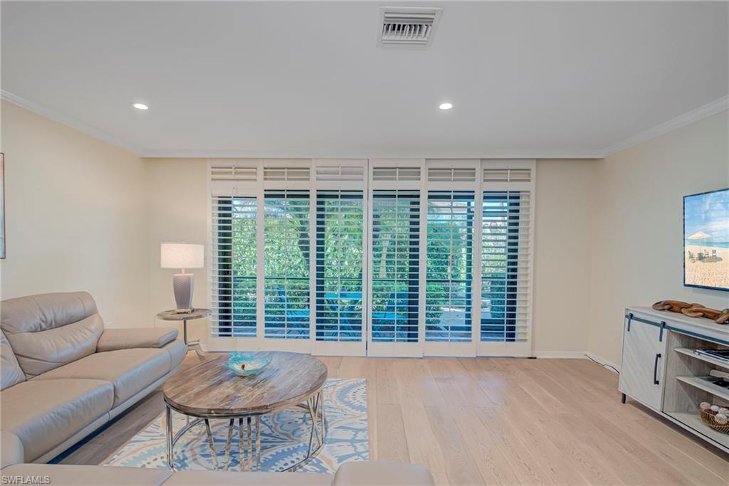 1070 6th Street South, Unit 1070 Naples, FL 34102 - Photo 15 of 41 Living area with ornamental molding, light wood-style flooring, plenty of natural light, and recessed lighting. The plantation shutters are accordian and can moved to the wall - and provide extra privacy while also allowing the light to come in.
