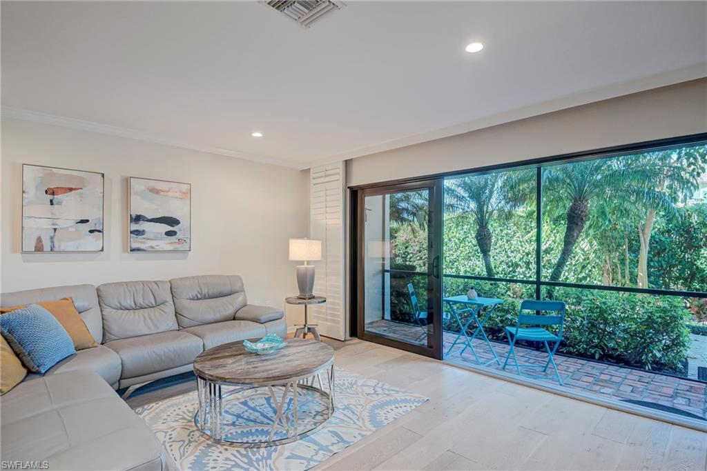 1070 6th Street South, Unit 1070 Naples, FL 34102 - Photo 16 of 41 Living room with wood finished floors, recessed lighting, and crown molding. Accordian shutters and impact doors! Screened-in lanai that has a door to go outside to the path- pool- carport.