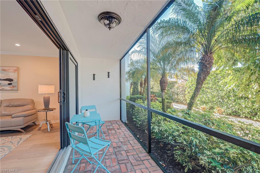 1070 6th Street South, Unit 1070 Naples, FL 34102 - Photo 17 of 41 Screened-in lanai patio space that has a fan and bike hooks- this leads to the pathway to the pool, carport, and guest parking in the back of the building Lush palms and landscaping as your view!