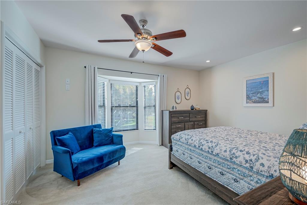 1070 6th Street South, Unit 1070 Naples, FL 34102 - Photo 23 of 41 Awesome window with tons of natural light coming in and views of the trees swaying outside. Carpeted bedroom featuring a ceiling fan, 2 closets, window treatments, and recessed lighting. The bed is a queen and the couch is a sleeper sofa. There are two end tables next to the bed on both sides.