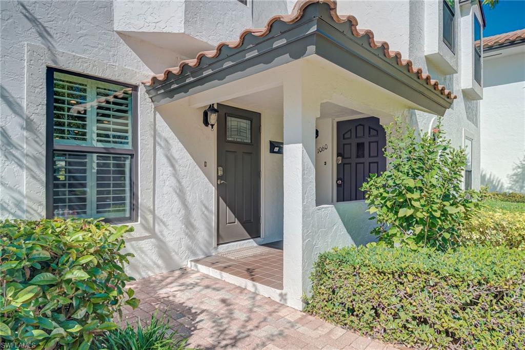 1070 6th Street South, Unit 1070 Naples, FL 34102 - Photo 2 of 41 View of exterior entry with stucco siding and a tiled roof. Entry area is elevated and lawn is landscaped.