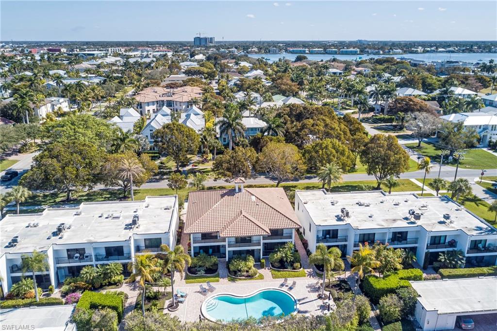 1070 6th Street South, Unit 1070 Naples, FL 34102 - Photo 6 of 41 Drone / aerial view of a pool with the complex behind. Carport and extra storage for the unit is on the right hand side in the middle.