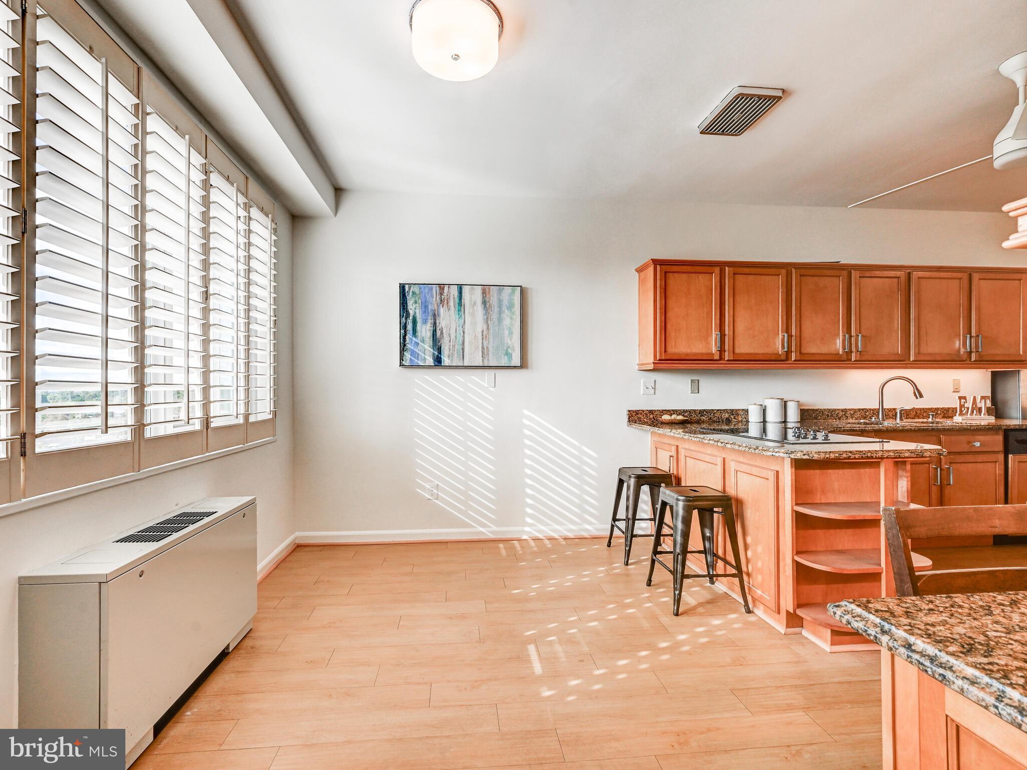 11 Slade Avenue, Unit 912 Baltimore, MD 21208 - Photo 12 of 31 a open kitchen with stainless steel appliances granite countertop a stove top oven a sink a dining table and chairs with wooden floor