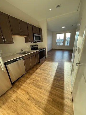a kitchen with stainless steel appliances wooden floors wooden cabinets and entryway