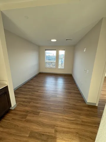 a view of empty room with wooden floor and window