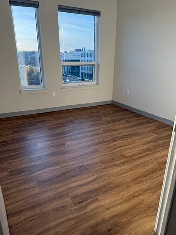 a view of an empty room with wooden floor and a window