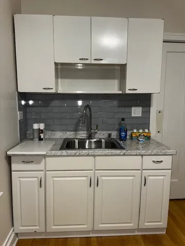 a kitchen with white cabinets and sink