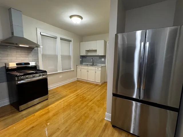 a kitchen with granite countertop a refrigerator and a stove top oven