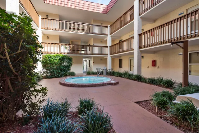 a view of a house with brick walls plants and large tree