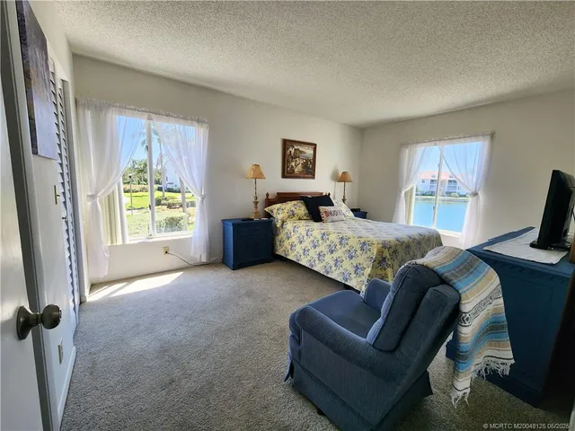 a bedroom with a bed and a flat tv screen on dresser